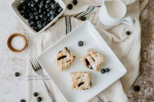 Blueberry Cream Pastry Puffins on plate surrounded by blueberries with other kitchen items around the plate