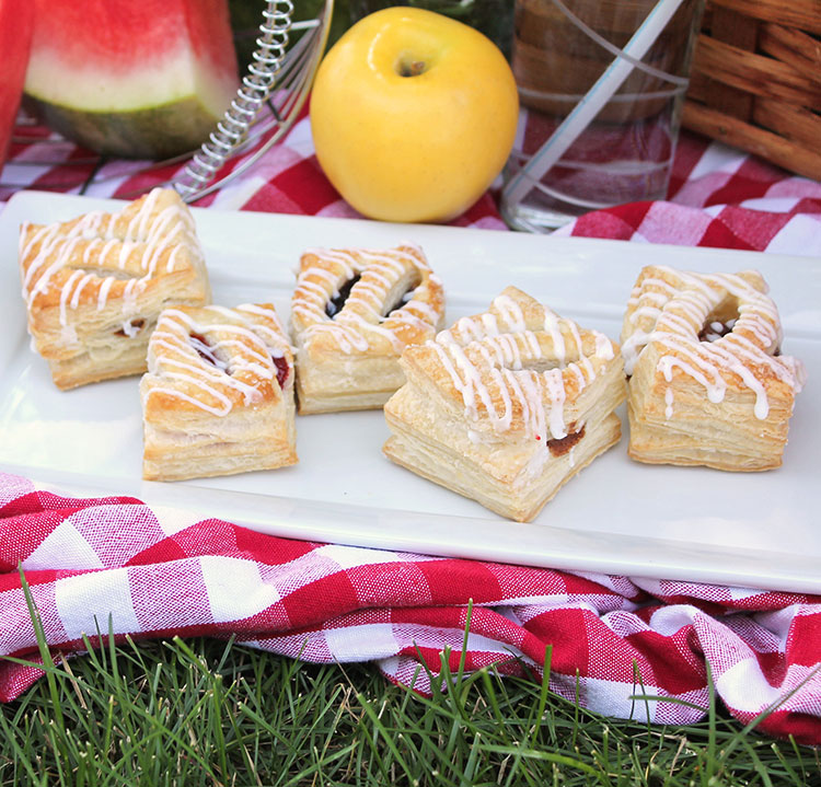 Five pastry puffins on a plate surrounded by picnic items